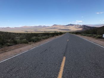 Road leading towards mountains against sky