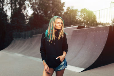 Beautiful young woman standing at skateboard park