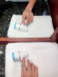 High angle view of woman hand holding hair dryer on towel by mirror