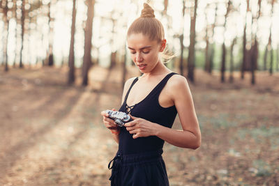 Woman holding camera while standing on field