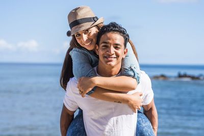 Portrait of happy friends at beach against sky