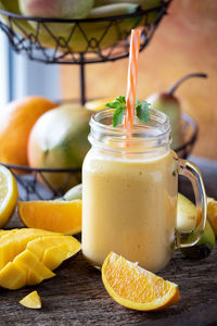 A jar mug filled with a refreshing healthy mango citrus smoothie.