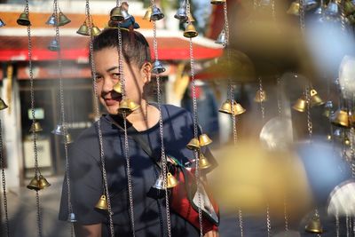 Portrait of woman seen through bells hanging at market