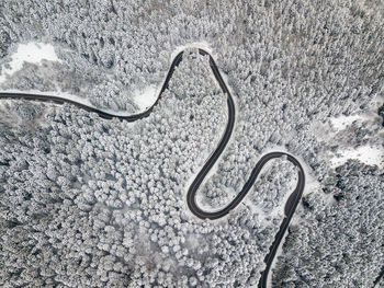 Aerial view of a road winding through snow covered forest