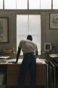 Rear view of male entrepreneur working at table in workshop