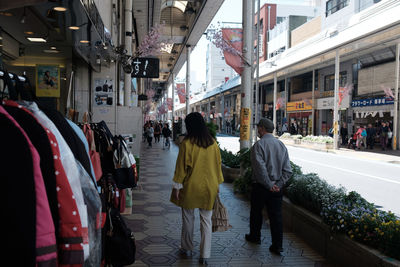 Rear view of people walking on street in city