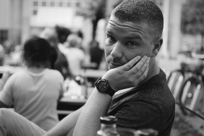 Bored young man with hand on chin sitting at restaurant