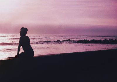 Silhouette woman standing at beach during sunset