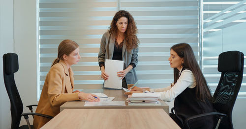 Large shot three females working on financial business goal showed on paper report in office. 