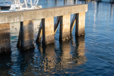 Wooden posts on pier over sea against blue sky