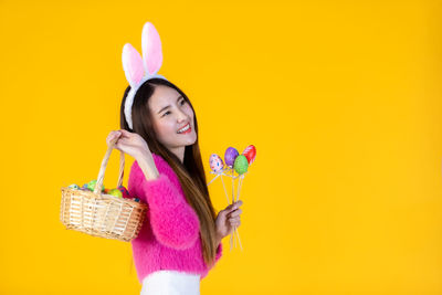 Portrait of woman with pink flowers against yellow background