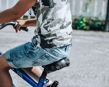 Low section of boy holding bicycle on street