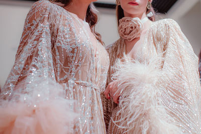 Elegant details of pastel pink haute couture boudoir dresses and a rose accessory around the neck