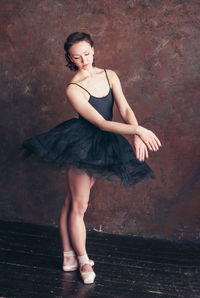 Full length of young woman dancing against wall