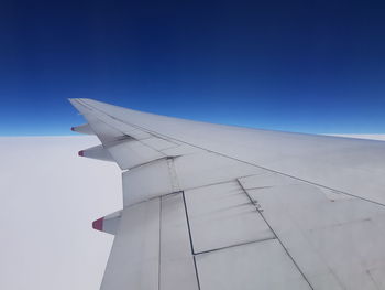 Low angle view of airplane flying against clear blue sky