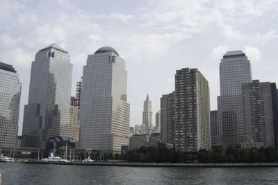 Buildings by river against sky in city