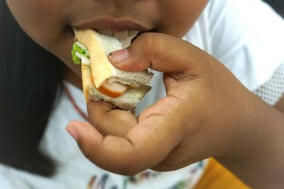 Midsection of girl eating sandwich at home