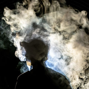 Man smoking cigarette against black background