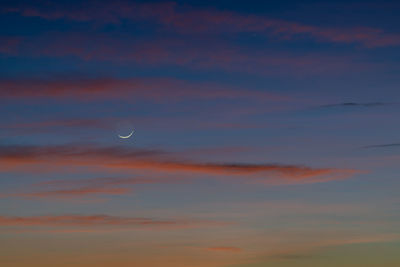 Low angle view of moon in sky at sunset