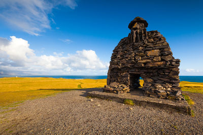 Stone sculpture on field against sky