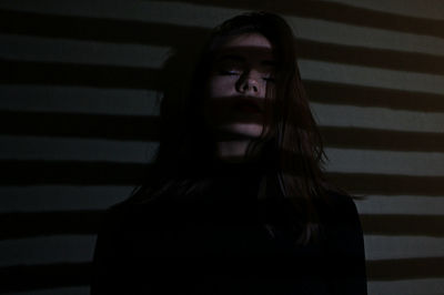 Shadow on young woman with closed eyes against wall