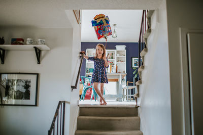 Cute young girl standing on stairs with happy birthday balloon