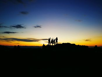 Silhouette people on landscape against sky during sunset