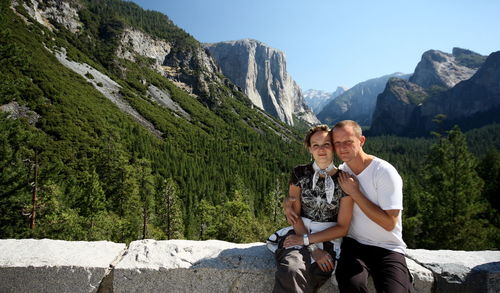 Portrait of man and woman sitting against mountains