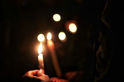 Close-up of hand holding lit candle