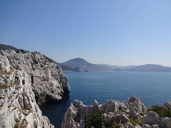 Scenic view of sea and mountains against clear blue sky