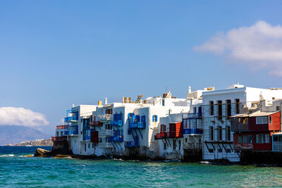 Buildings by sea against sky