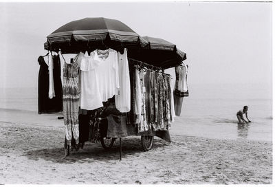 Man swimming in sea by clothes store on beach