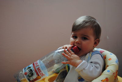 Portrait of cute boy holding bottle at home