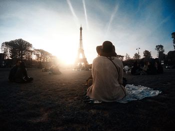 Rear view of people sitting by tower in city