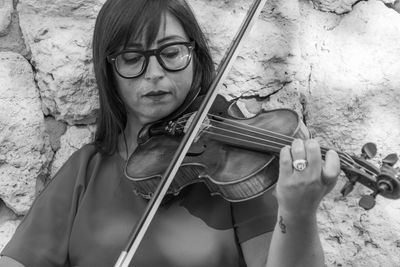 Close-up of woman playing violin against wall
