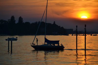 Silhouette sailboats in sea against sky during sunset