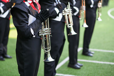 Student brass band prepare to prefrom musical in school green field. ensemble of musicians