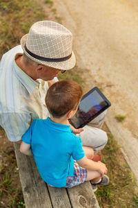 Rear view of father and son using mobile phone