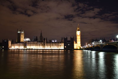 Illuminated bridge over river against sky in city at night