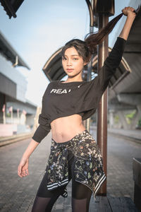 Portrait of beautiful young woman standing against wall