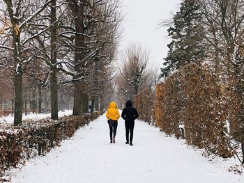 Rear view of people walking on snow covered land