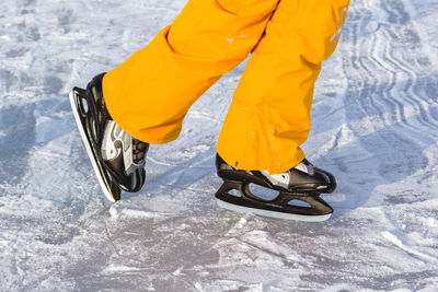 Low section of person wearing ice skates on snow