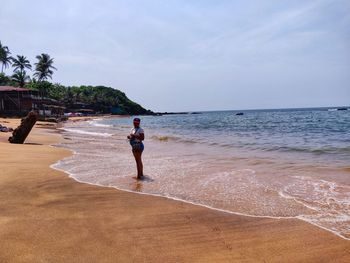 Full length of woman standing on beach against sky