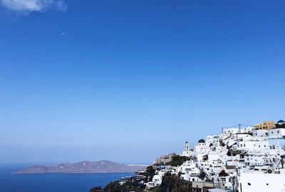 Town by sea against clear blue sky