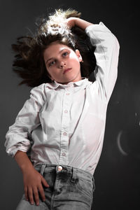 Portrait of girl standing against black background