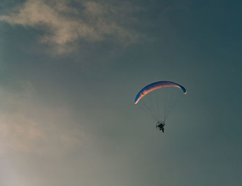 Low angle view of person paragliding against sky