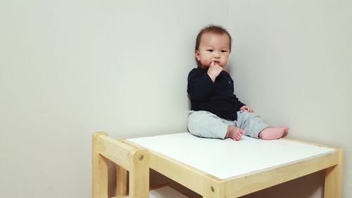 Cute baby boy sitting on table at home