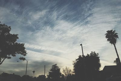 Low angle view of silhouette trees against cloudy sky