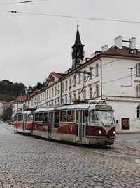 Train on railroad tracks by buildings in city against sky