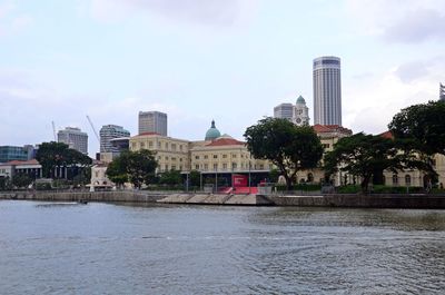 Buildings by river against sky in city